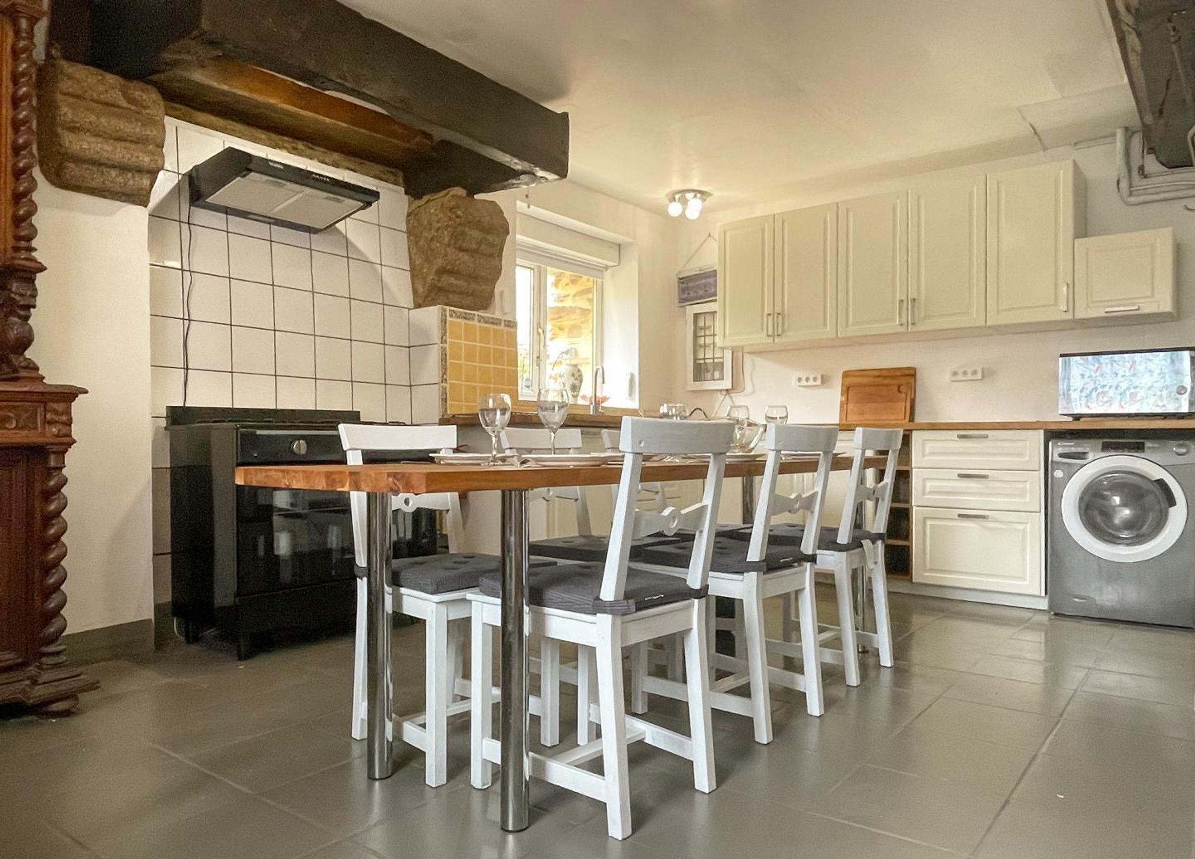 Une cuisine équipée d’une table à manger, de chaises, d’un lave-linge et d’une cuisinière.
