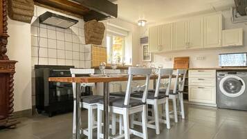 Une cuisine équipée d’une table à manger, de chaises, d’un lave-linge et d’une cuisinière.