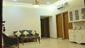 A spacious living room with a sofa, wooden cabinets, and a chandelier. - Family Ties Homestay (Varanasi)