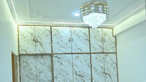 A bedroom with a large bed, a marble-patterned wardrobe, and a chandelier. - Family Ties Homestay (Varanasi)