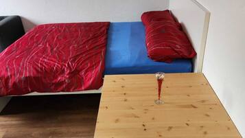 Une petite pièce avec un lit, une table en bois et une chaise.
