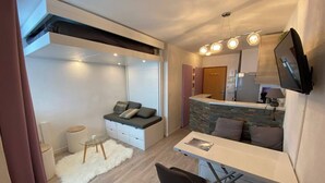 A compact living space with a sofa, a dining table, and a kitchen area. - Ski in, ski out APPT in the resort center (Les Belleville)