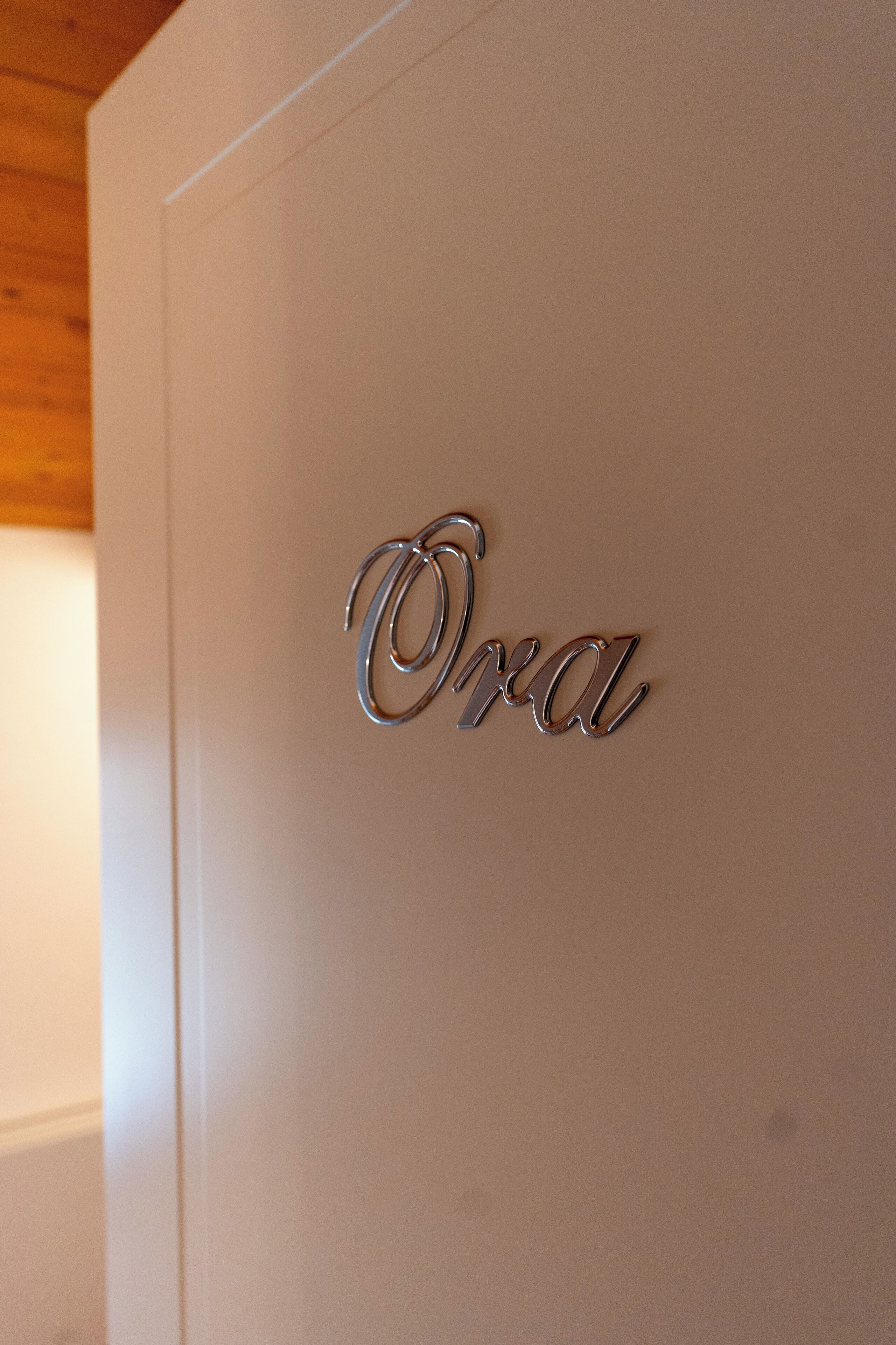 Ein metallisches Schild mit dem Wort „Oda“ an einer weißen Wand.