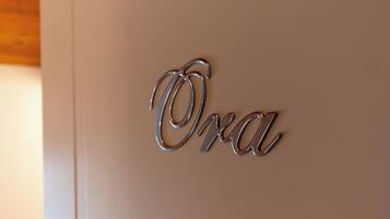 Ein metallisches Schild mit dem Wort „Oda“ an einer weißen Wand.