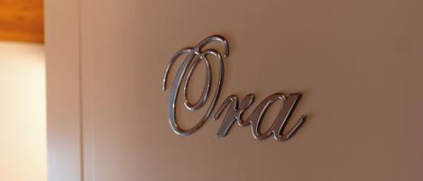 A metallic sign with the word "Oda" on a white wall.