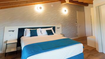 Ein Schlafzimmer mit Holzboden, einem Bett mit blauer und weißer Bettdecke, einem Nachttisch und einer Tür.