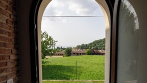 An arched doorway leading to a patio with a grassy lawn and a brick wall on one side. - 4 Elementi Relais (Lonato del Garda)