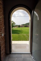 Un arco d'ingresso conduce a un patio con prato verde e un muro in mattoni su un lato.