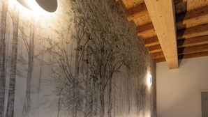A bedroom with a bed, a headboard, a wall-mounted light, and a mural of trees. - 4 Elementi Relais (Lonato del Garda)