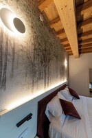 Una camera da letto con un letto, una testiera, una lampada a parete e un murale raffigurante alberi.