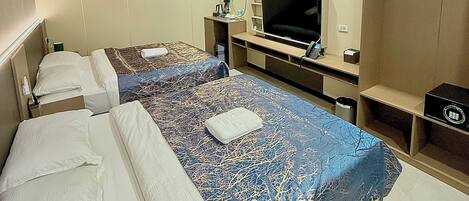 A hotel room with two beds, a TV, a wardrobe, and a desk with a chair.