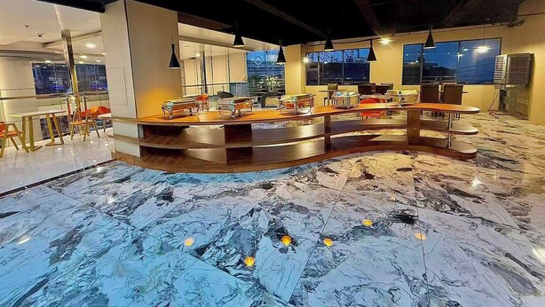 Un área de bar moderna con una barra curva, asientos y ventanas grandes.