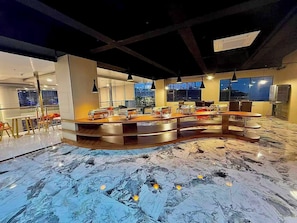 A modern bar area with a curved counter, seating, and large windows. - Skyport Hotel (Pasay)