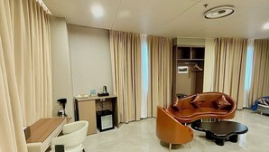 Habitación de hotel con comedor, sofá, una mesita y kitchenette.