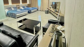Una habitación de hotel con cama, zona de estar con mesa, televisión y minibar.