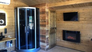 Een moderne kamer met een glazen lift, een open haard, een televisie en een houten interieur.