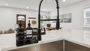 Een moderne keuken met een roestvrijstalen spoelbak, een zwarte kraan en een zeepdispenser.