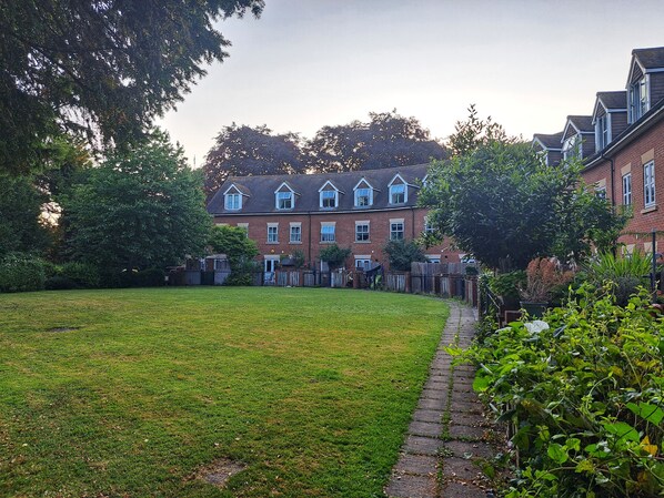 A residential building with a brick facade, multiple windows, and a well-maintained lawn.