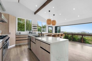 Una cocina moderna con una isla grande, armarios de madera y vistas al exterior.
