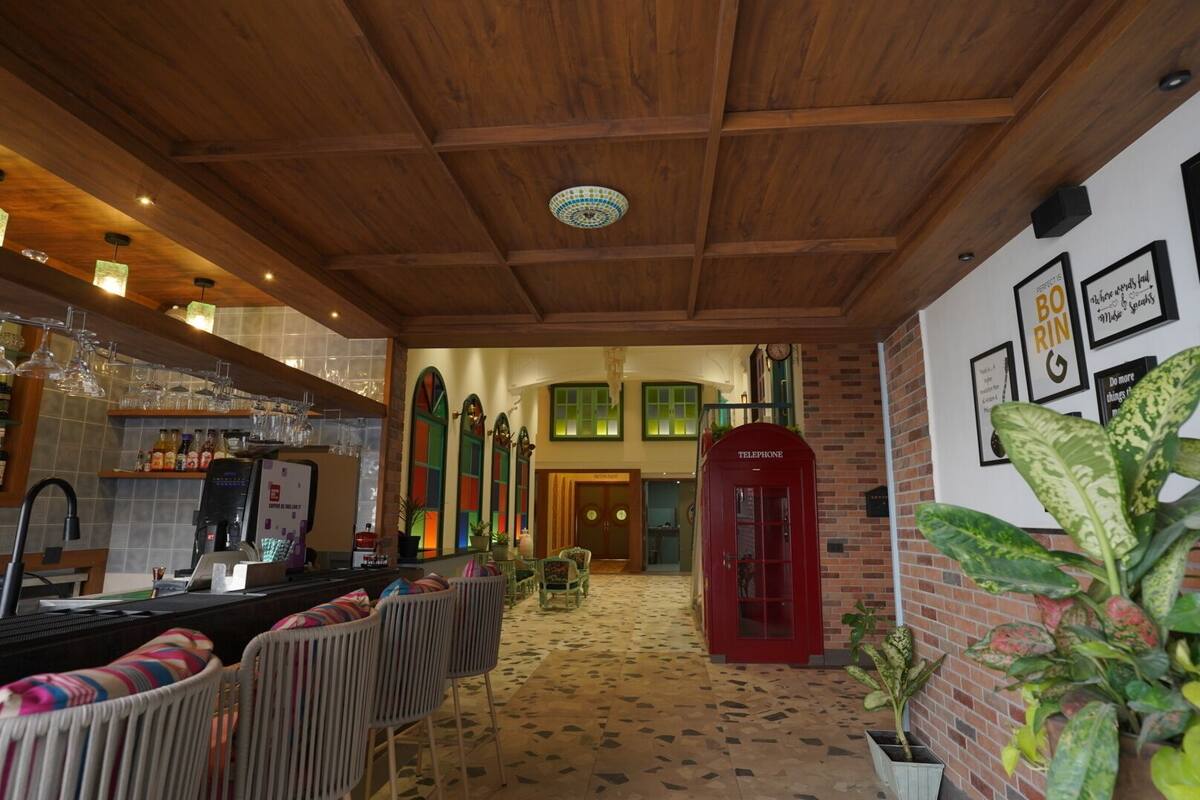A cozy bar area with wooden ceiling, a red telephone booth, and a seating area with chairs.