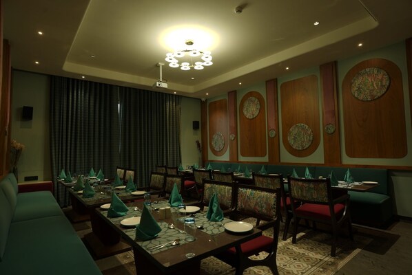 A dining area with a long table set for a meal, surrounded by chairs with patterned upholstery. - Shri Rawatpura Sarkar Seva Ashram (Haridwar)