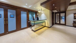 A reception area with a counter, wooden cabinets, and a modern ceiling design. - Shri Rawatpura Sarkar Seva Ashram (Haridwar)