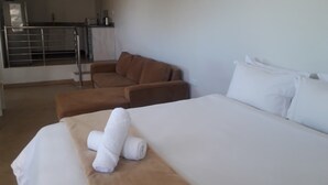 A hotel room with a bed, a brown sofa, and a small kitchenette in the background. - Bedsitter Bed & Breakfast in Nyanga near popular Attractions (Nyanga)