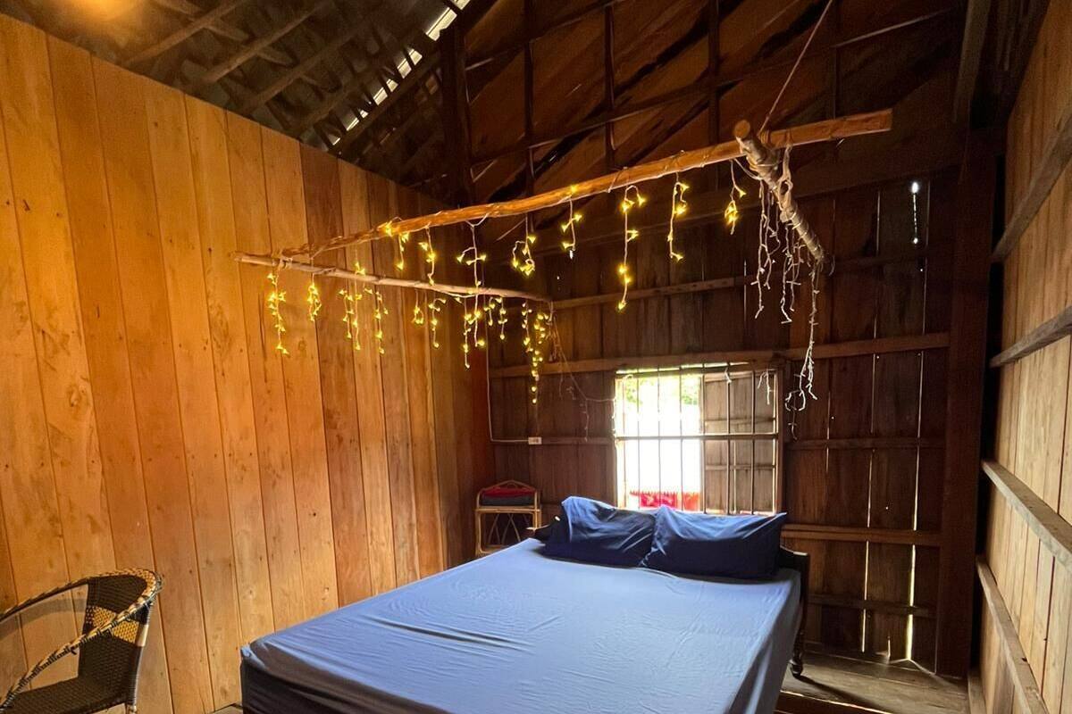 A wooden room with a bed, a chair, and string lights.