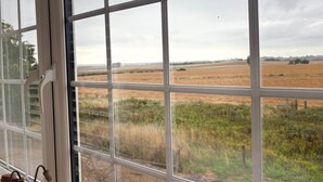 A view through a window with a grid pattern, revealing a rural landscape with fields and distant trees. - Idyllic Studio in Tenterden (Tenterden)