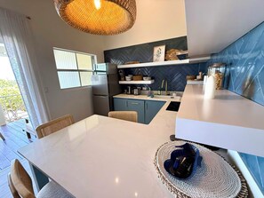 Una cocina moderna con un refrigerador empotrado, un lavamanos y una zona de comedor con mesa y sillas.