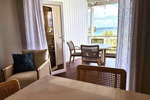 A room with a view of the ocean, a dining table with chairs, and a sofa with cushions. - Lantana Sea La Vie - by ZenBreak (Weston)