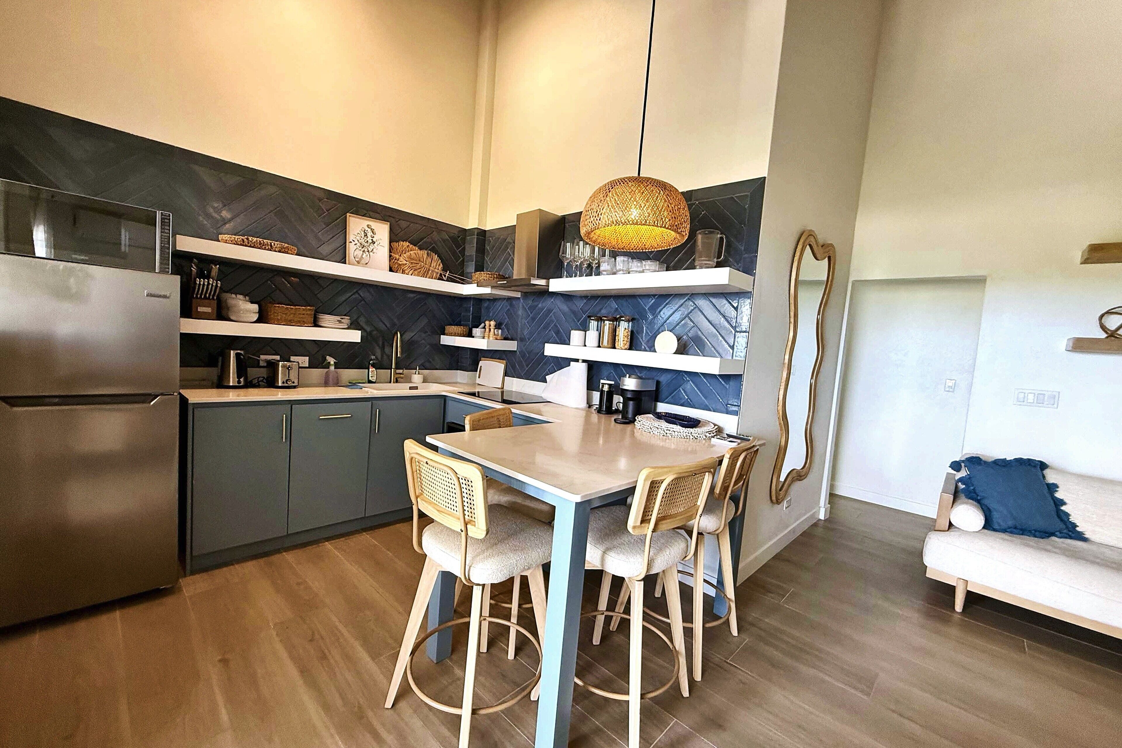A modern kitchen with a dining area, featuring a refrigerator, stove, and wooden chairs.