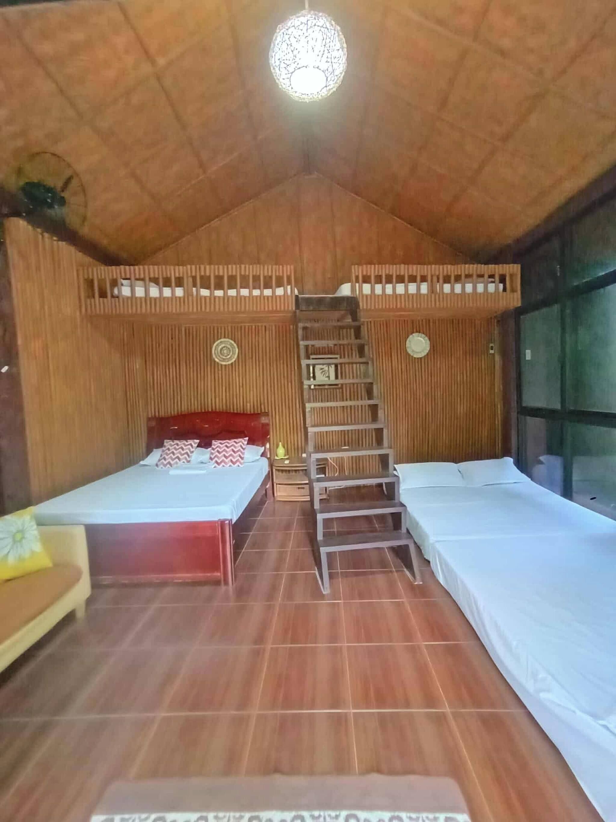 Una stanza accogliente con due letti, una scala e un soffitto in legno.