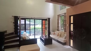 A spacious living area with a sofa, coffee table, and a staircase leading to an upper level. - Your Tagaytay Escape Here in Mendez, Where Nature, Relaxation, and Fun Await (Mendez)
