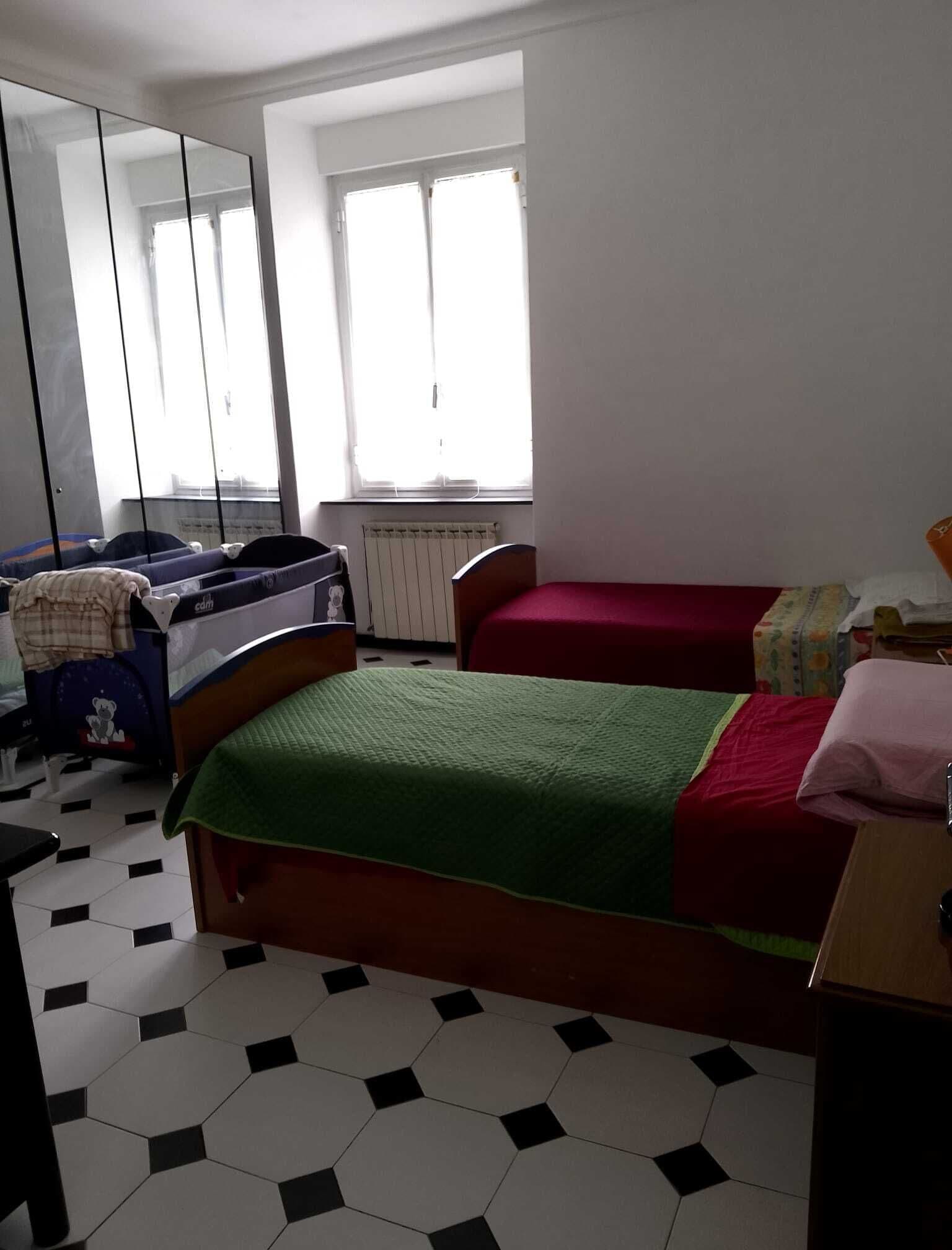 Ein Schlafzimmer mit zwei Betten, einem großen Spiegel, einem Heizkörper und einem Fenster mit Jalousien.