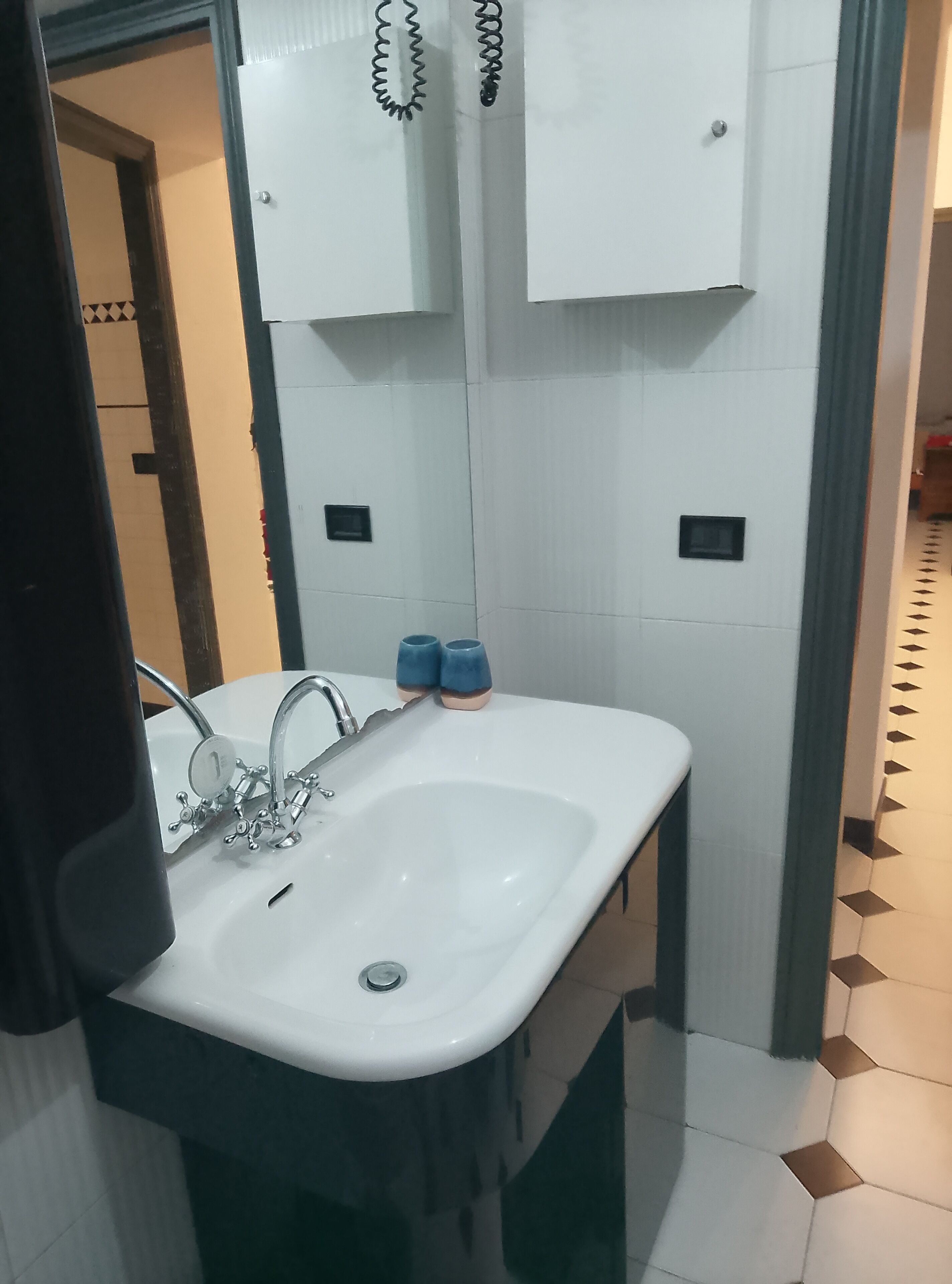 A bathroom with a white sink, a mirror, and a towel rack.