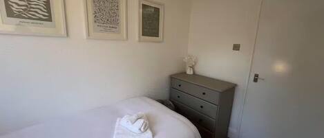 A bedroom with a bed, a dresser, and three framed artworks on the wall.