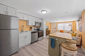 A modern kitchen with white cabinets, stainless steel appliances, and a central island with stools.