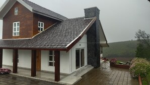 A two-story house with a tiled roof and a stone chimney.