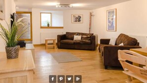 A spacious living room with a brown leather sofa, a wooden coffee table, and a small side table. There is a potted plant on the left and a framed picture on the wall. - Loft Bonziers - authentic alpine experience (6p, sauna) (Peisey-Nancroix)