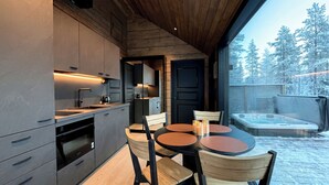 Una cocina moderna con comedor, un jacuzzi y vistas a árboles cubiertos de nieve.