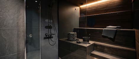 A modern bathroom with a glass-enclosed shower, a wooden vanity with a towel rack, and a built-in bench.