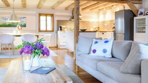 Una sala moderna con un sofá, una mesa de centro con un jarrón de flores y un comedor con sillas y una mesa.