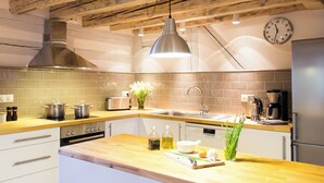Cocina moderna con encimera de madera, electrodomésticos de acero inoxidable y una lámpara colgante.