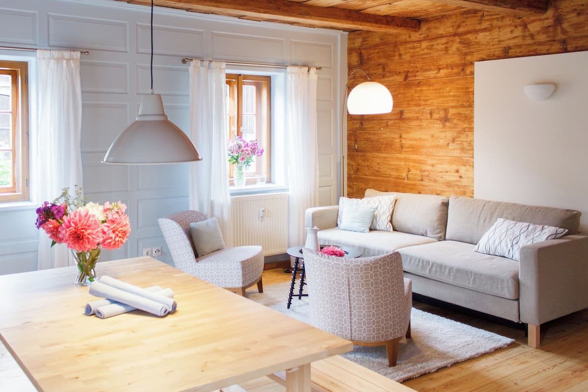 Una sala de estar acogedora con techo de madera, un sofá, una mesa de centro y una silla.