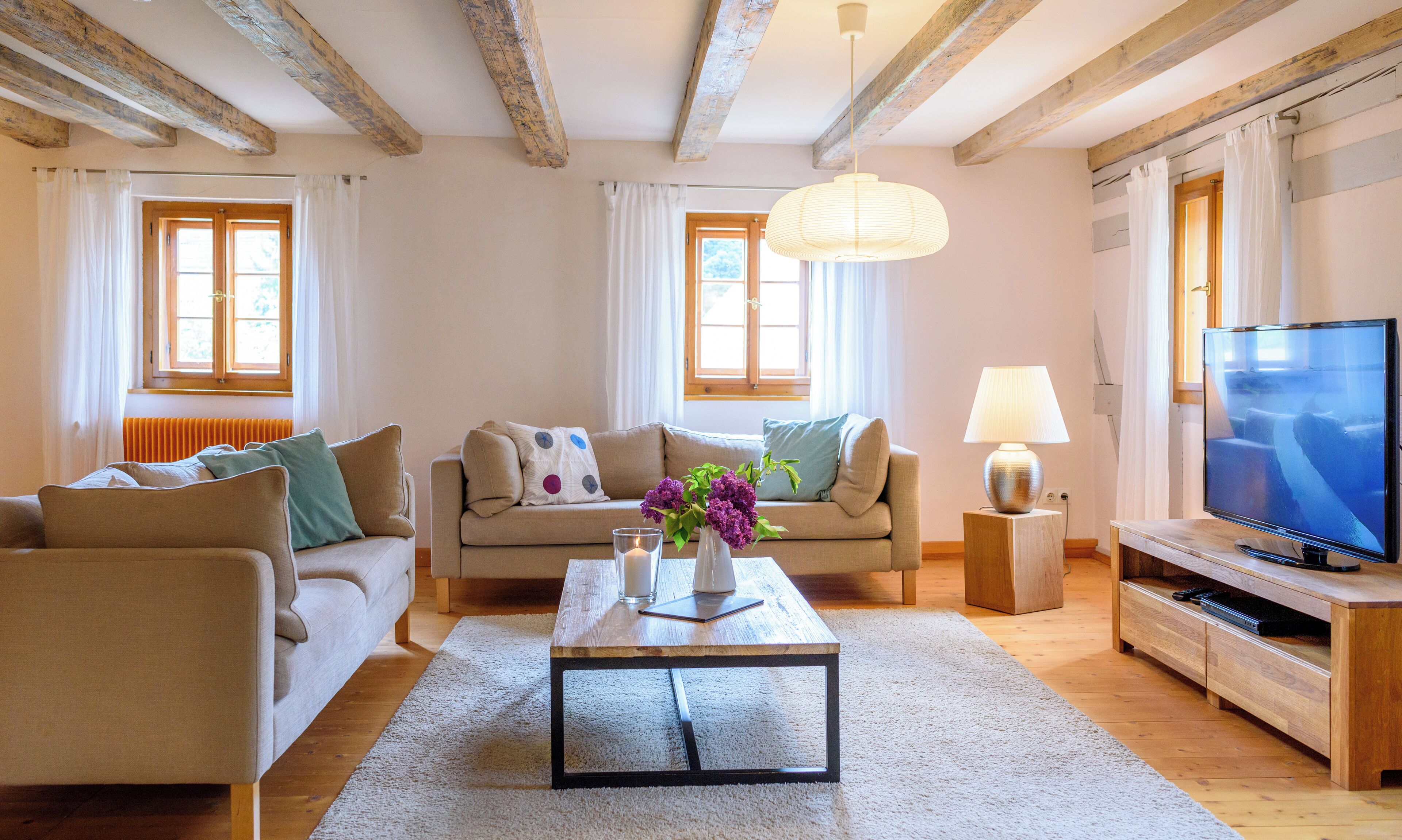 A living room with a sofa, a coffee table, a TV, and a lamp.