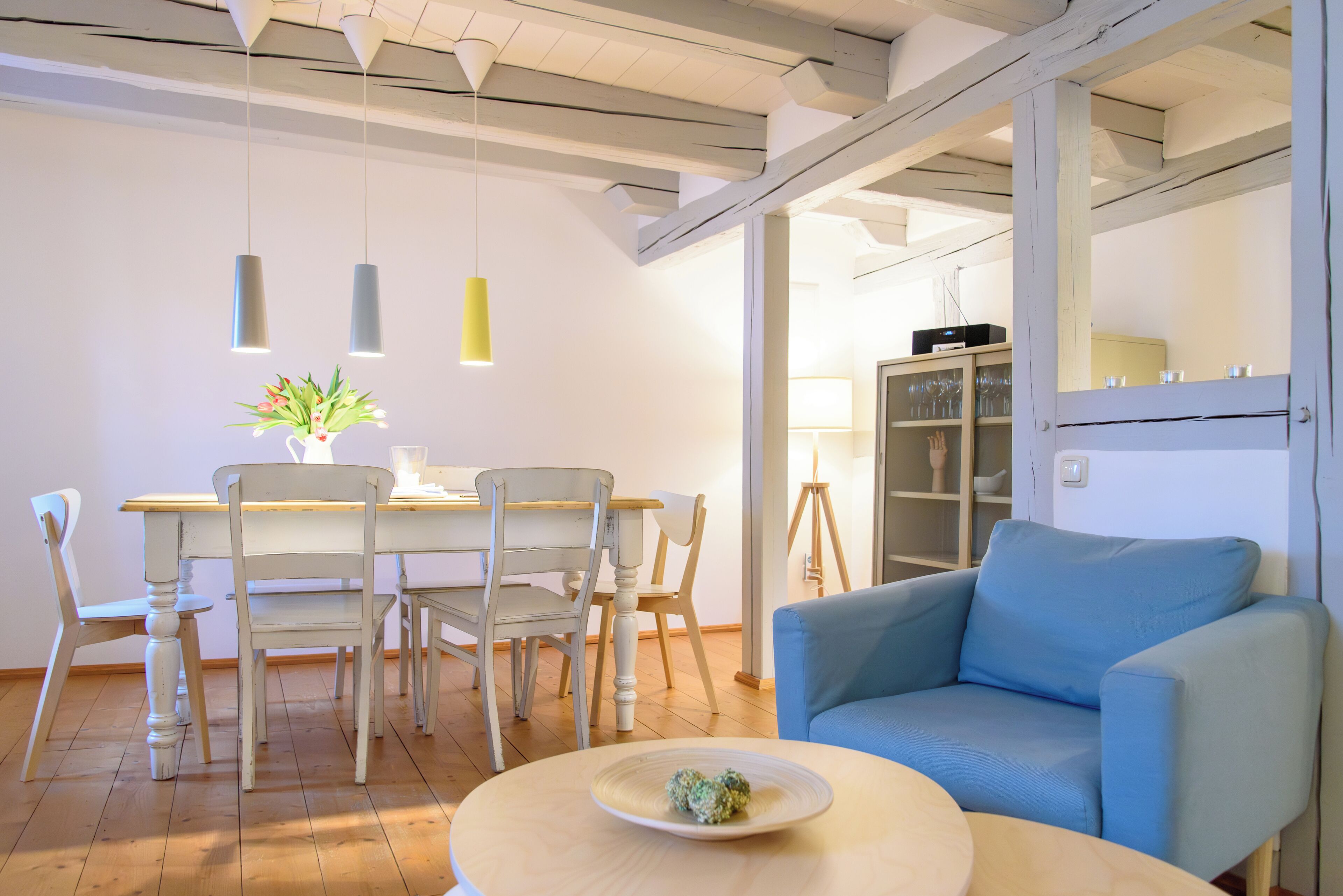 A modern dining area with a round table, white chairs, and pendant lights.