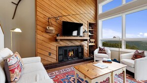A cozy living room with a fireplace, a flat-screen TV, and a large window offering a scenic view. - Highlands 24 with Wintergreen Advantage (Wintergreen)