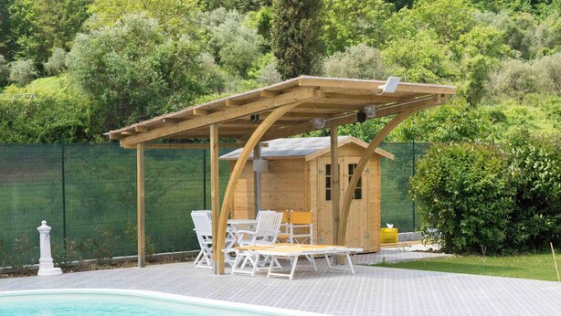 A pool area with a wooden pergola, lounge chairs, and a small wooden structure.