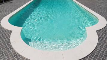 A rectangular swimming pool with a white edge, surrounded by a tiled deck.